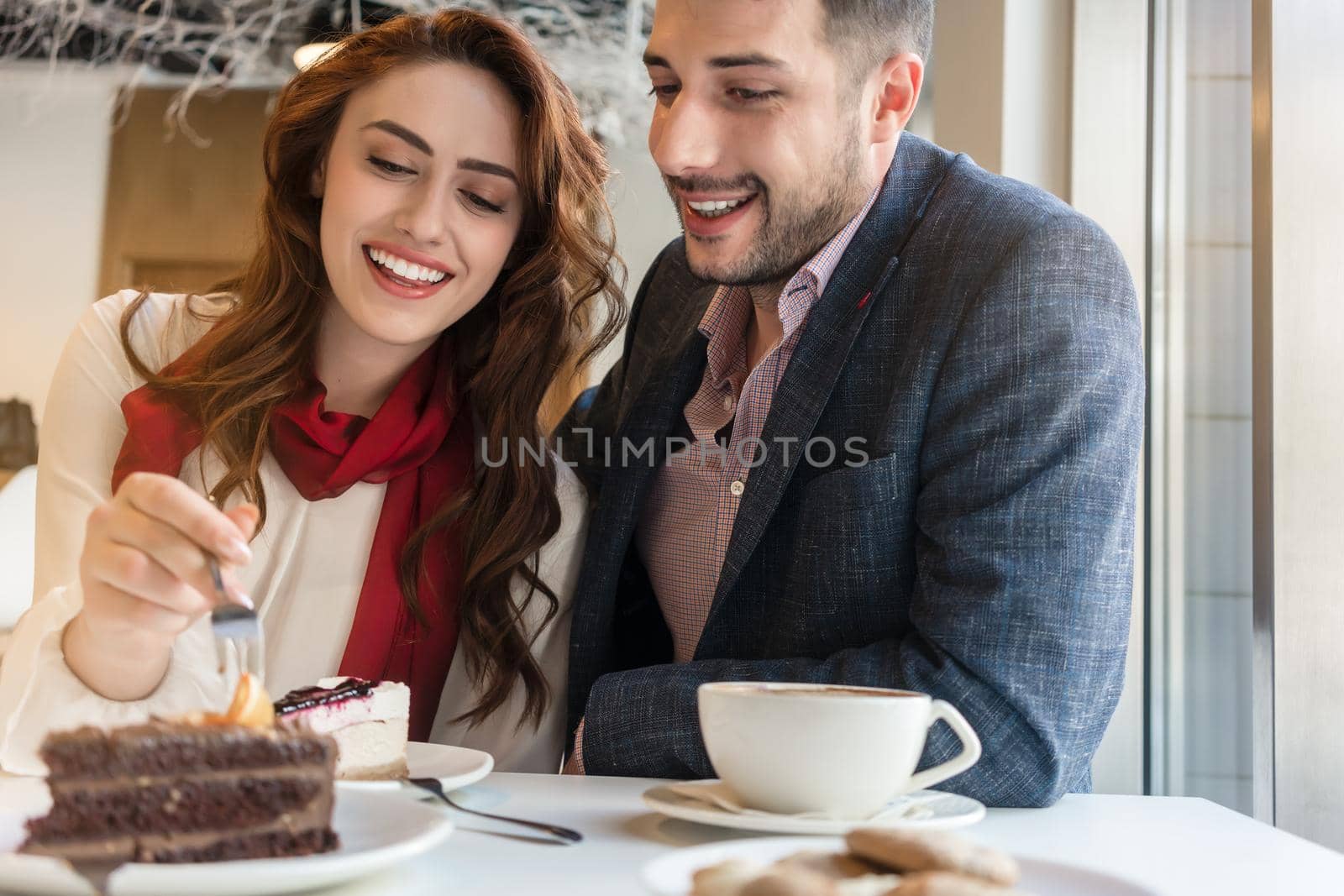 Delicious layered cake served with coffee on the table of a young couple in love during romantic date in a trendy cafeteria