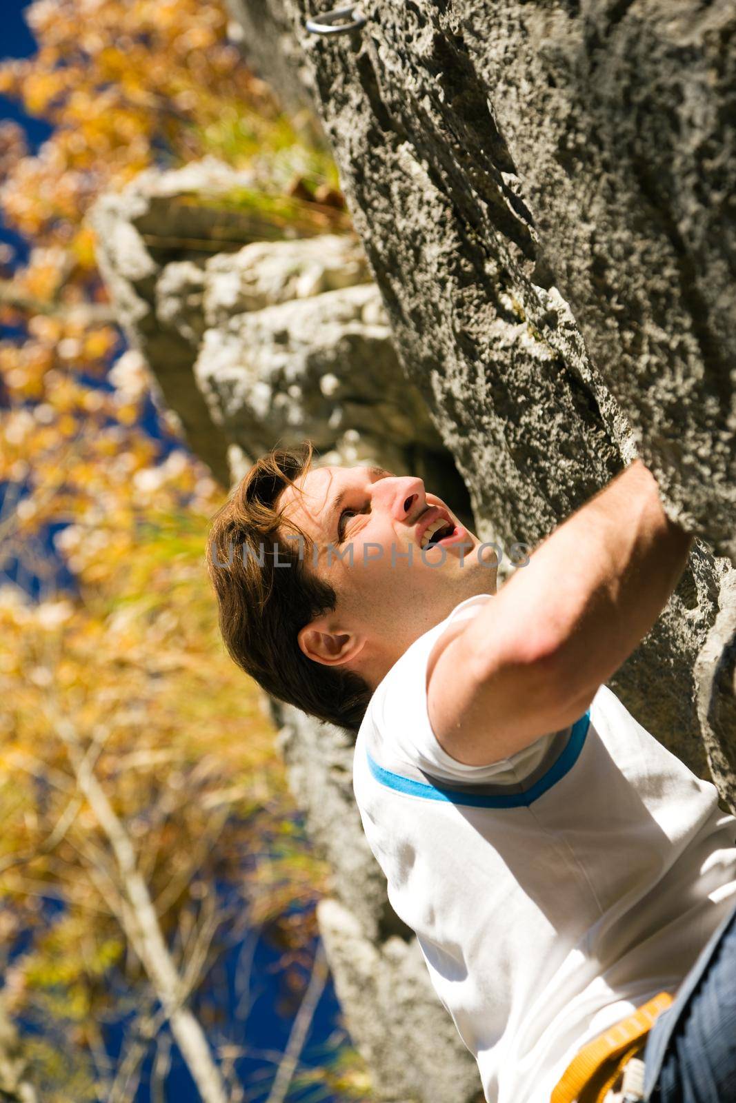 Man climbing a rock short before reaching the summit