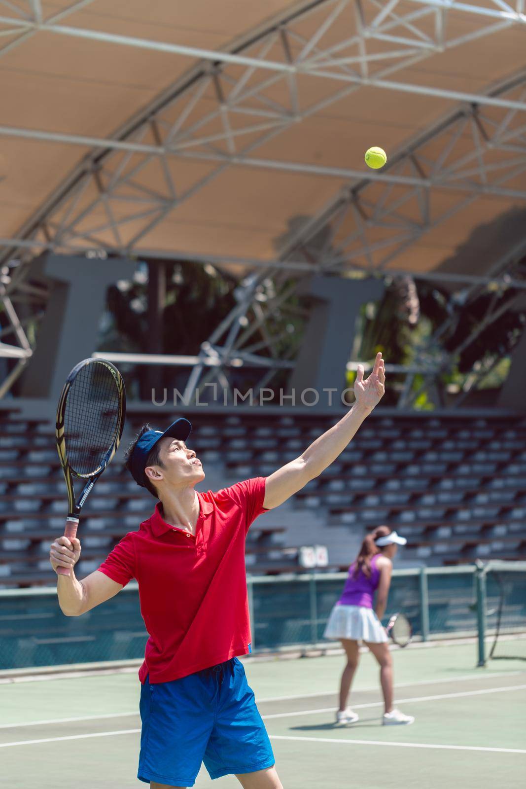 Asian tennis player ready to serve at the beginning of a doubles match by Kzenon