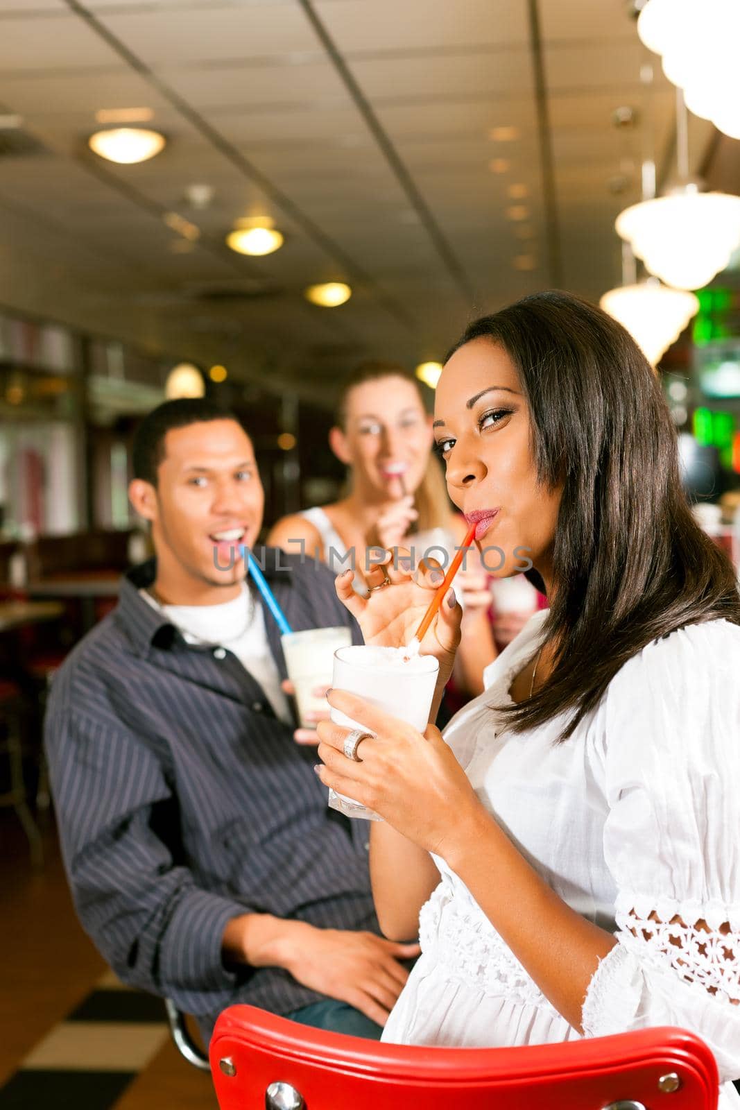 Friends drinking milkshakes in a bar by Kzenon