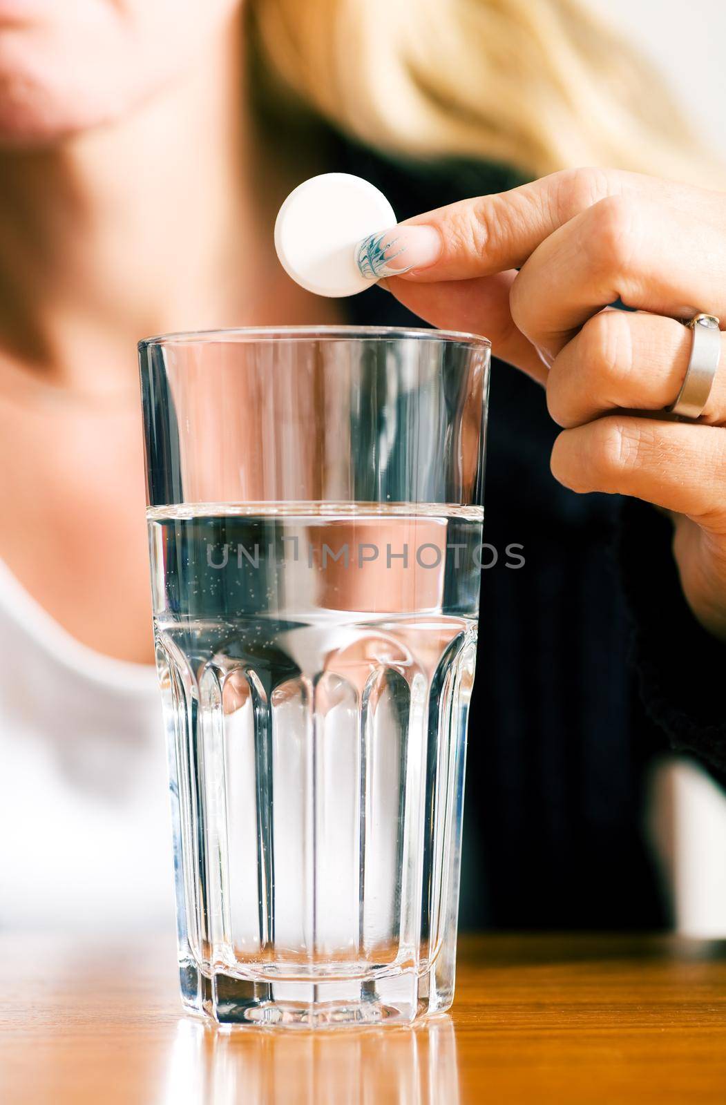 Woman ready to drop a pill into a glass of water (macro)