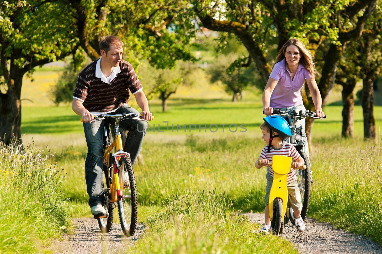 Family with boy child having a weekend excursion on their bikes on a summer day in beautiful landscape