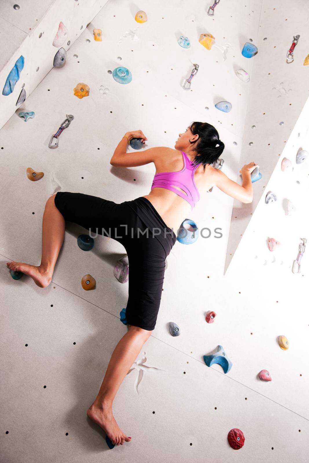 Woman exercising arms and upper body at a climbing wall in a gym