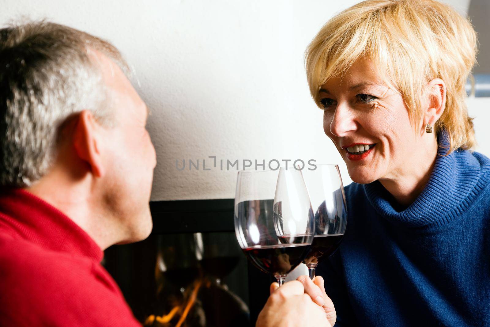 Mature couple having fun clinking glasses with red wine in a romantic setting