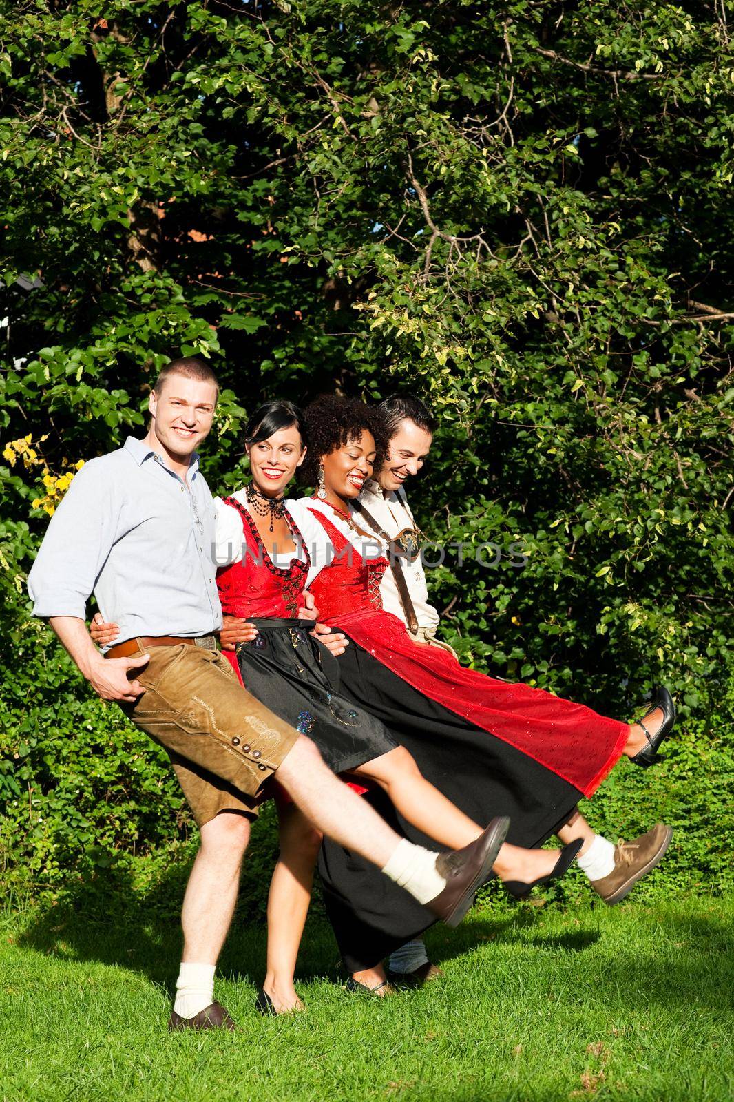 Group of four people - two Couples - in traditional Bavarian dress, Lederhosen and Dirndl, in summer