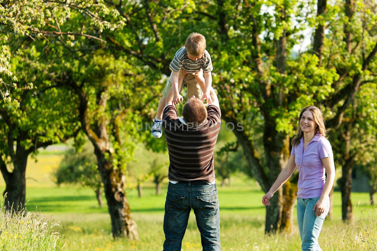 Family having a walk outdoors in summer by Kzenon