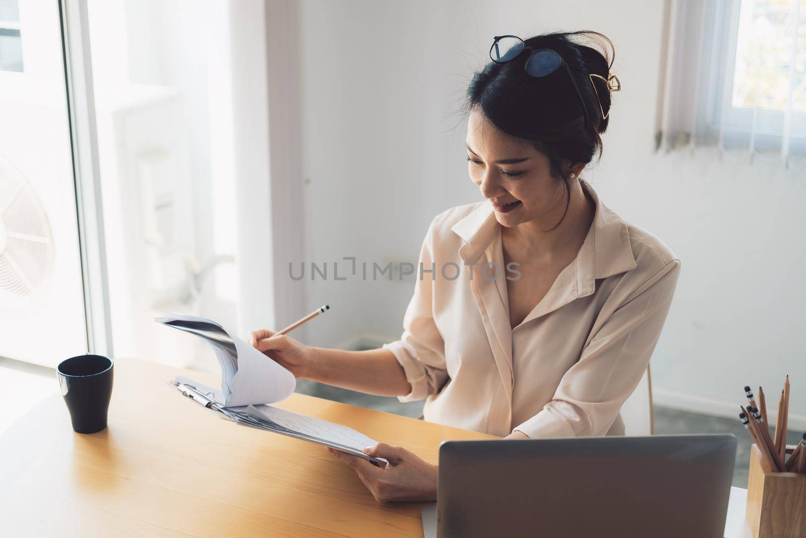 Female asian businesswoman analyzing the business report with laptop computer in the office. by nateemee