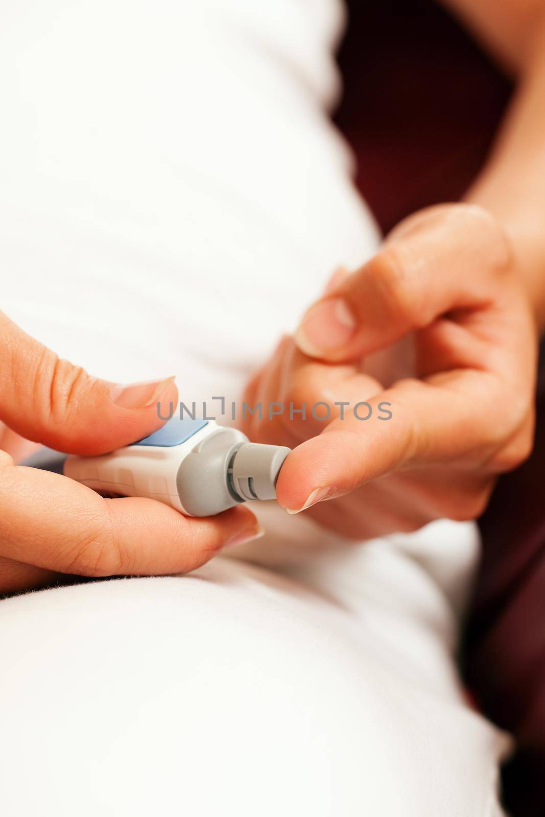 Woman taking a blood sample from her finger for a blood glucose level test that shows whether or not she has diabetes