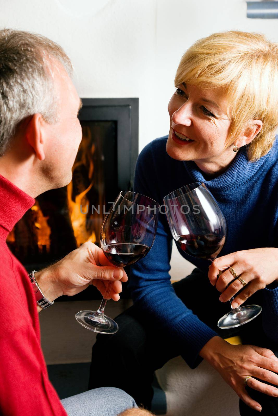 Mature couple having fun clinking glasses with red wine in a romantic setting
