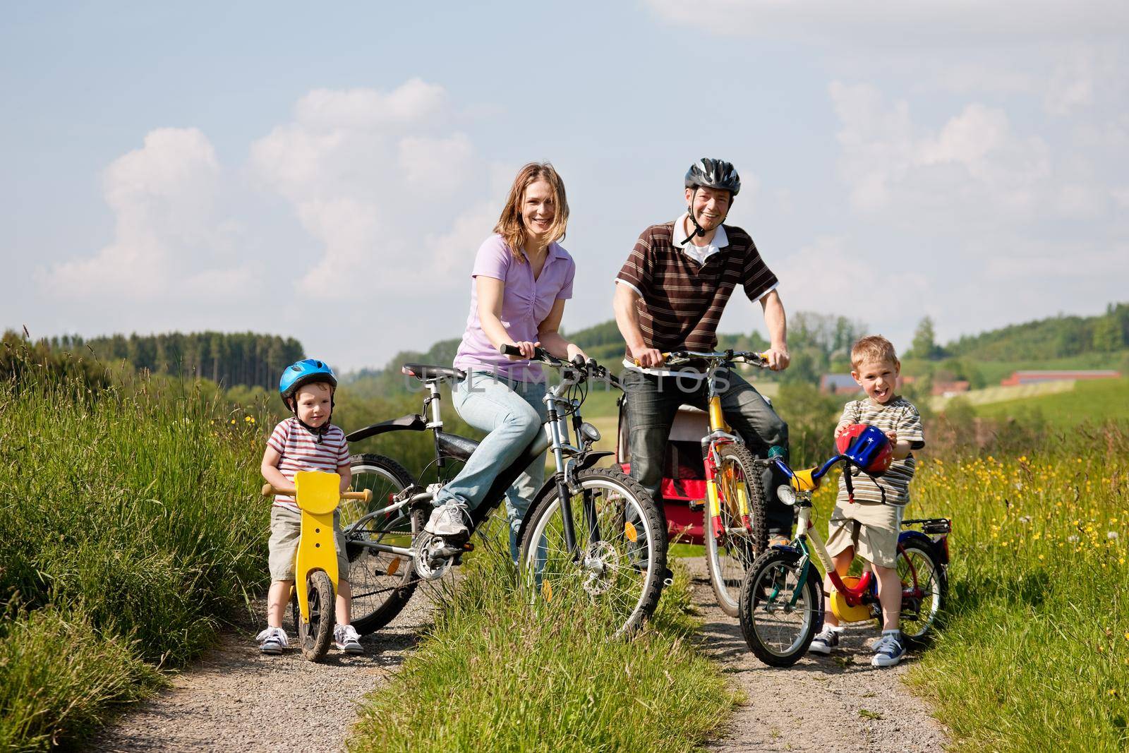 Family riding bicycles in summer by Kzenon