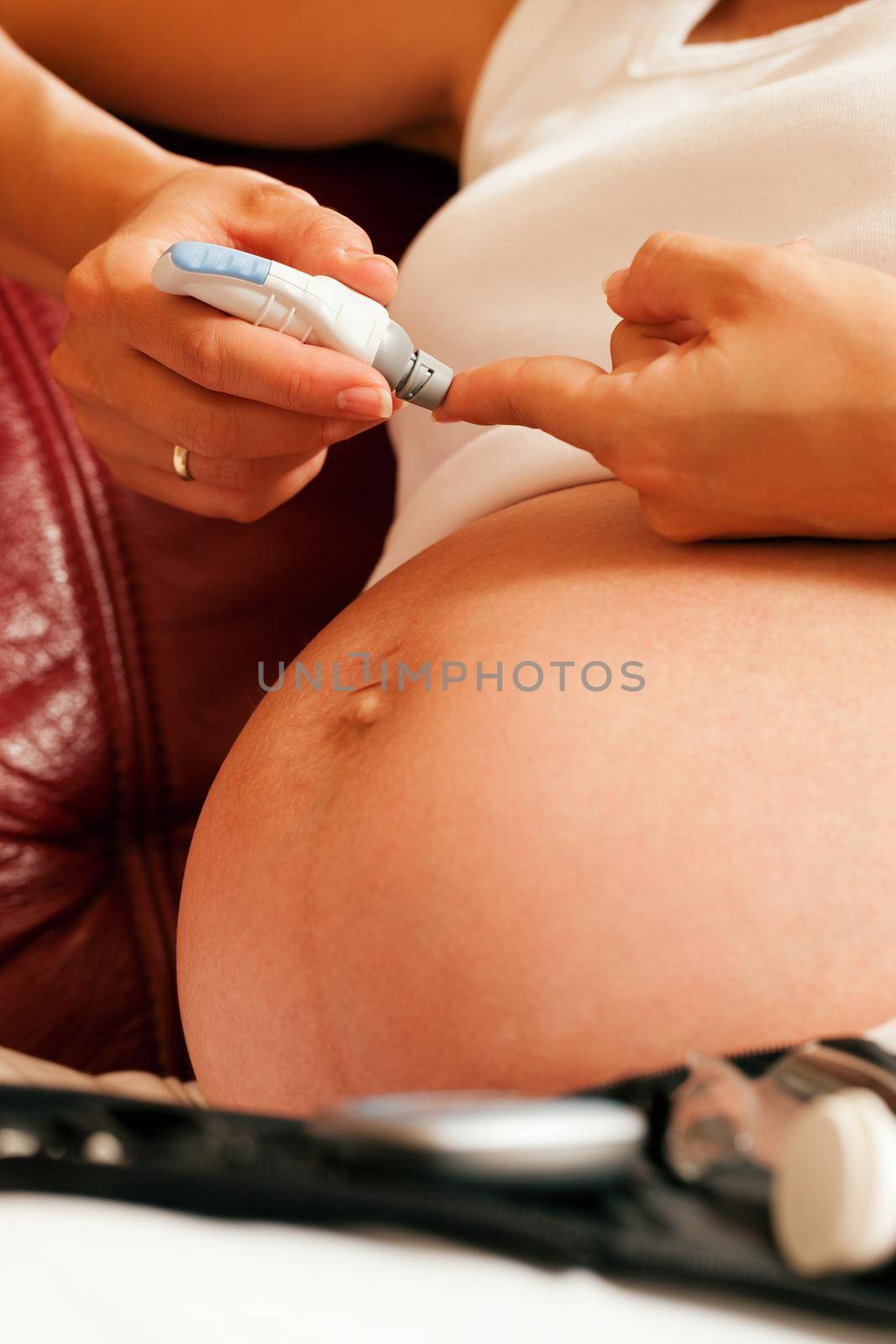 Pregnant woman testing glucose for diabetes by Kzenon