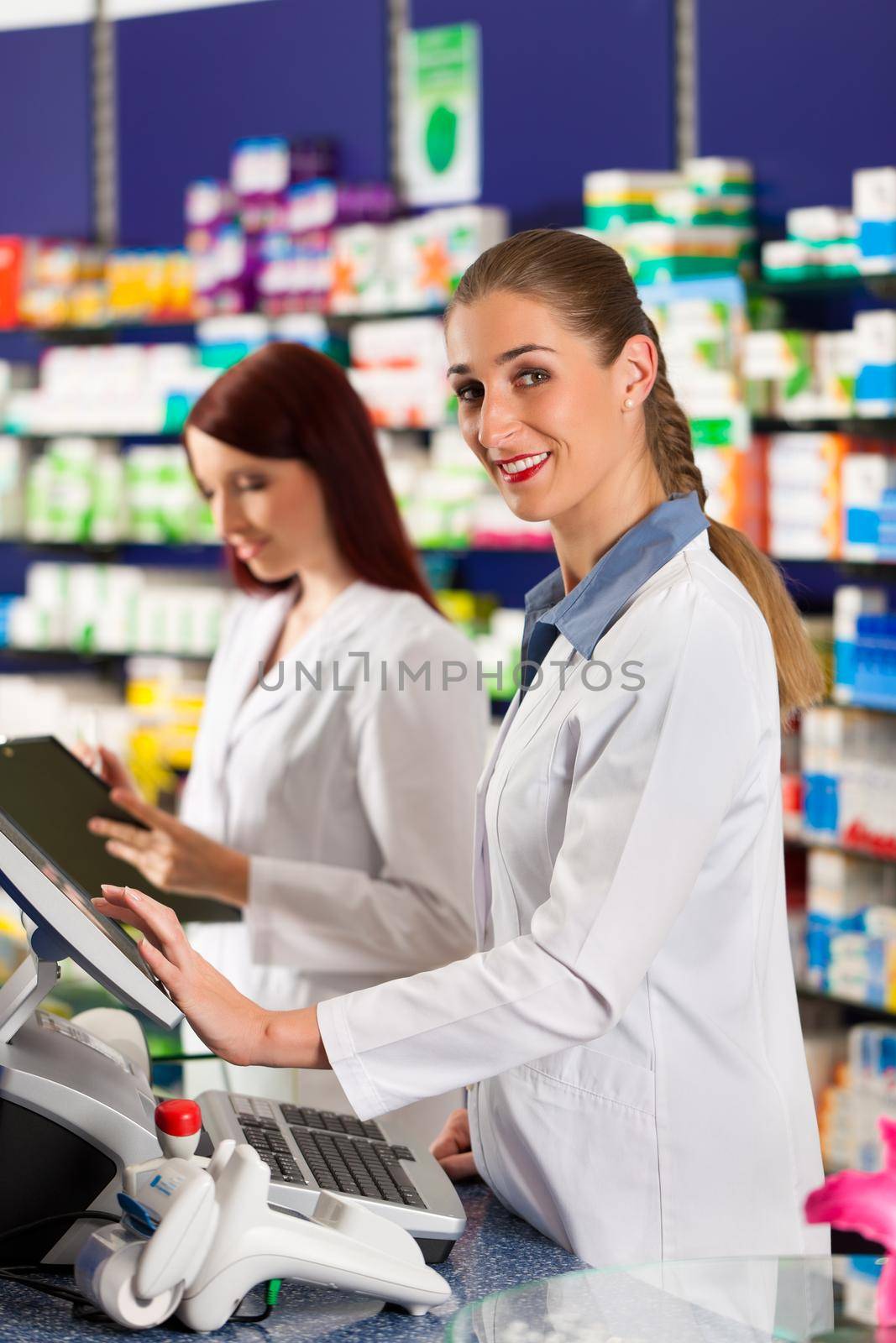 Pharmacist with assistant in pharmacy by Kzenon