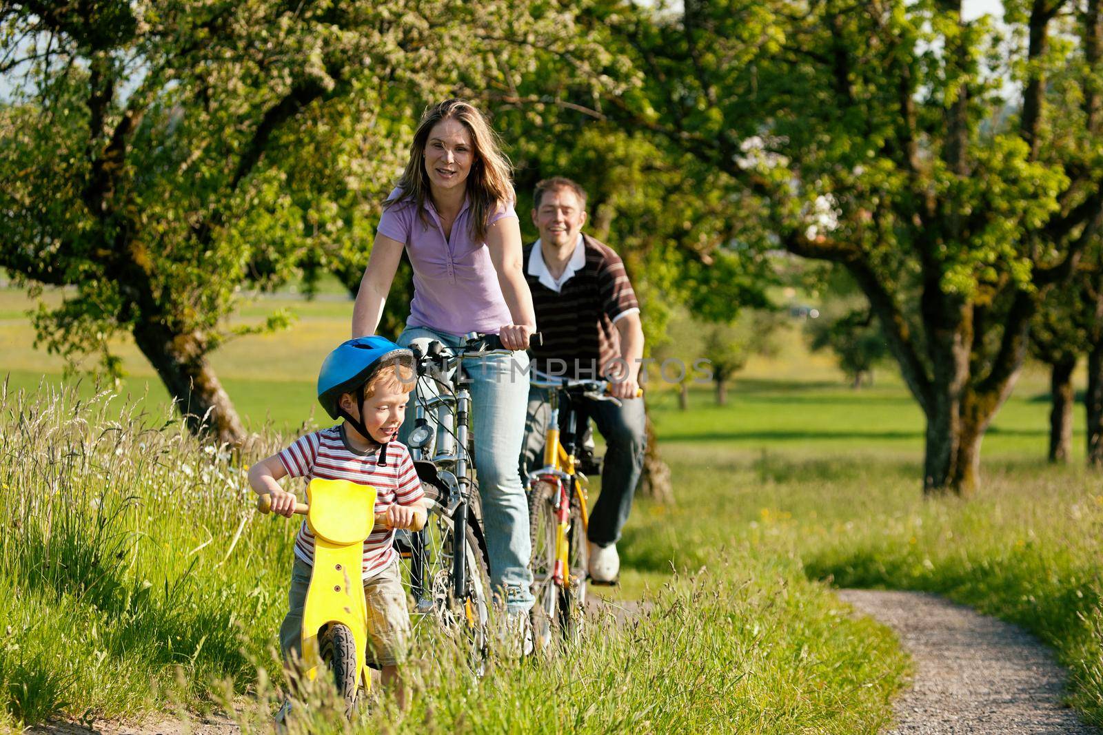 Family riding bicycles in summer by Kzenon