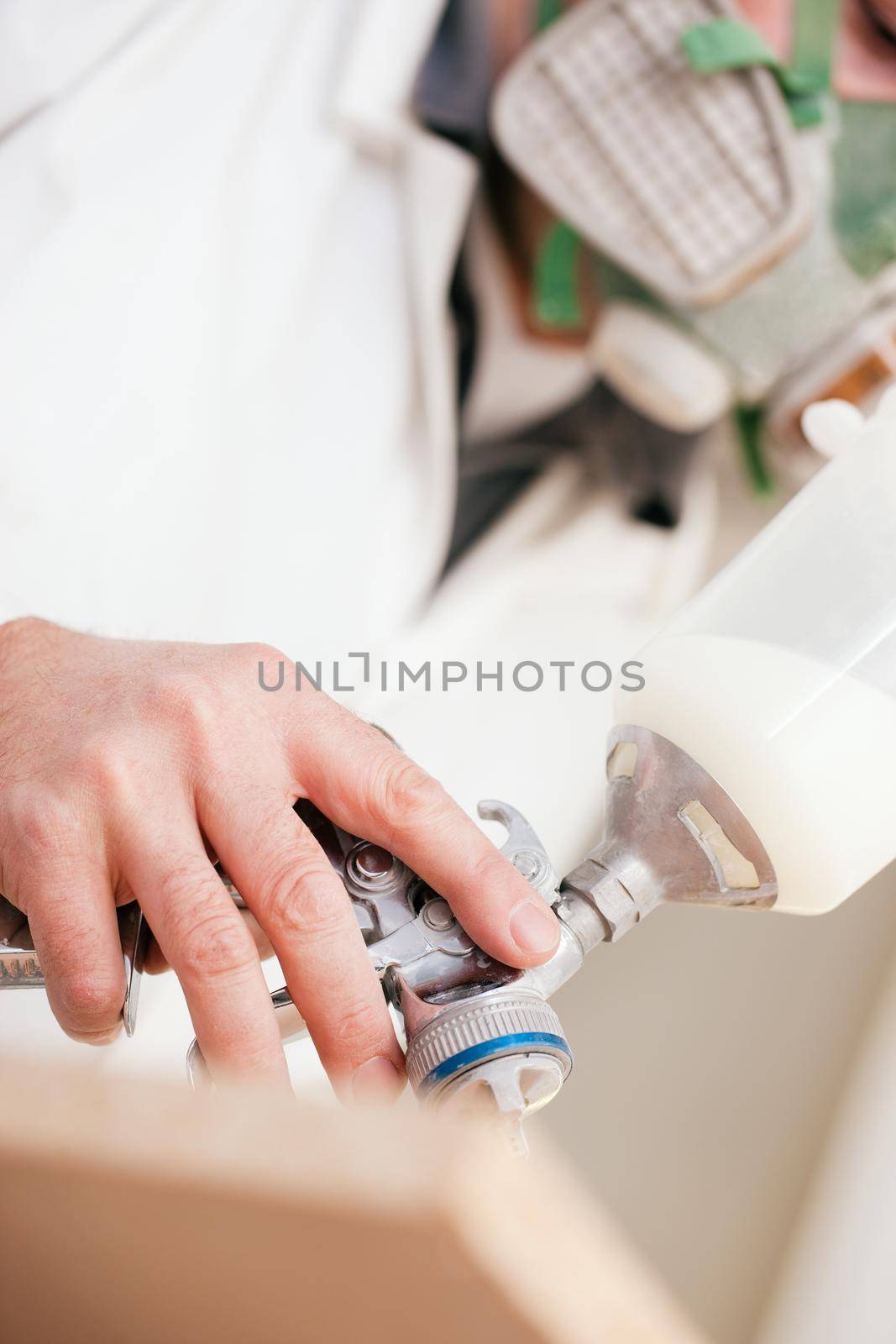 Carpenter in his paint room spraying a piece of wood to be used in his workshop later