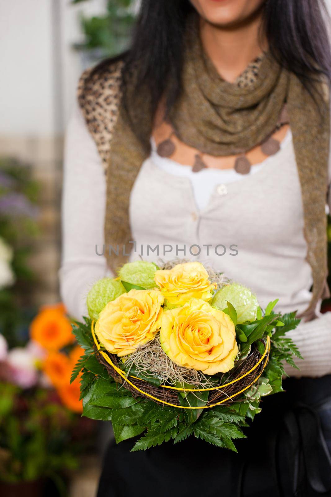 Female florist in flower shop or nursery presenting her plants on display