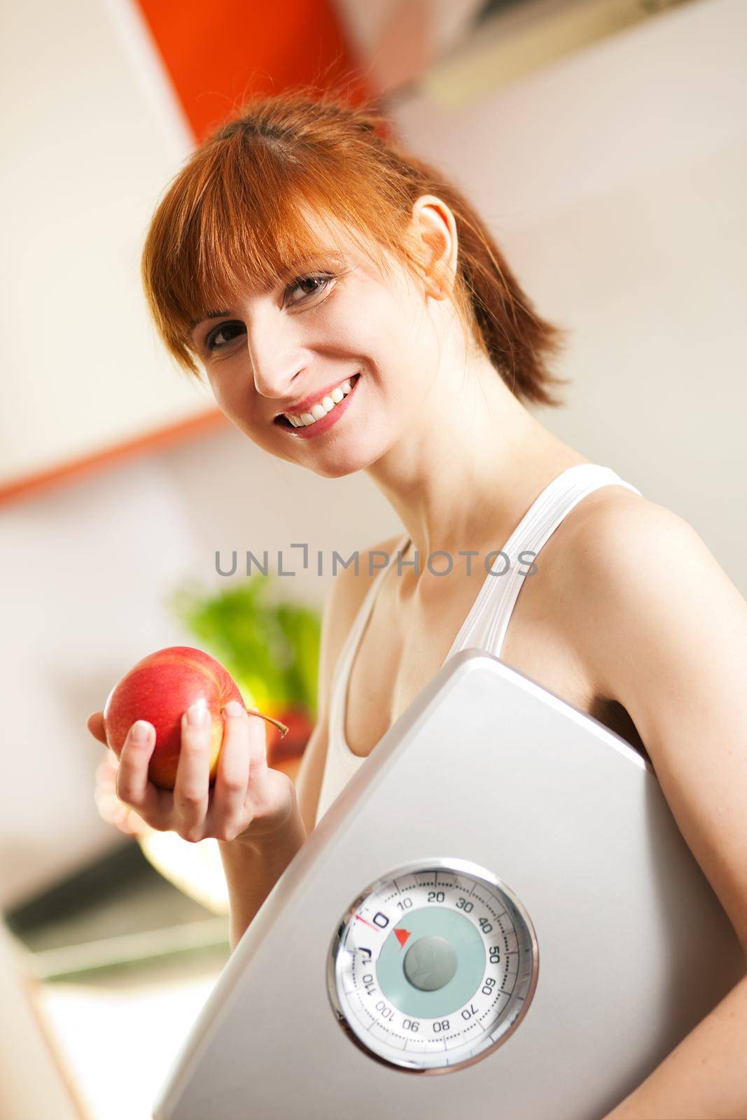 Thin and beautiful woman (only torso) measuring her waist with a tape measure, in the background fruit in a bowl