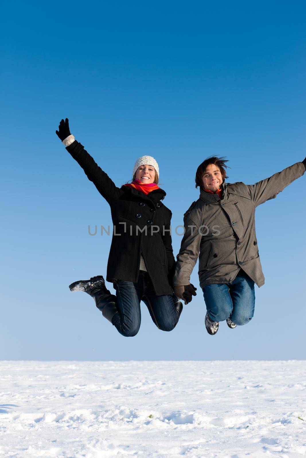 Couple - man and woman - jumping high on a winter day