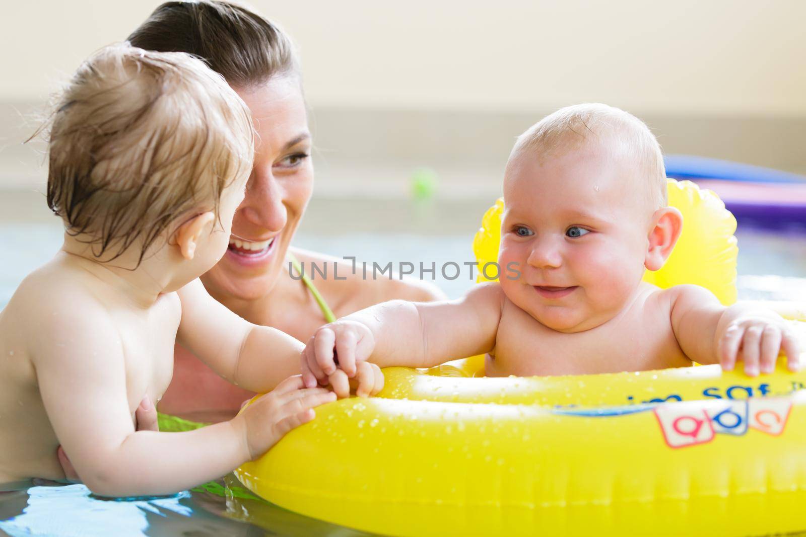 Mums and their children having fun together playing with toys at baby swimming lesson