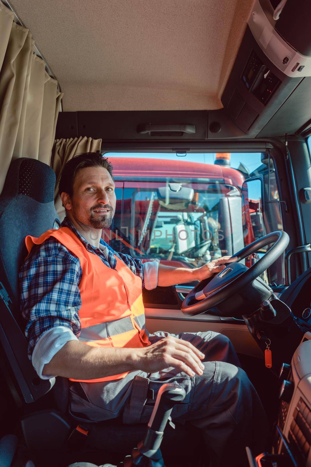 Lorry or truck driver sitting in the cabin of his vehicle driving