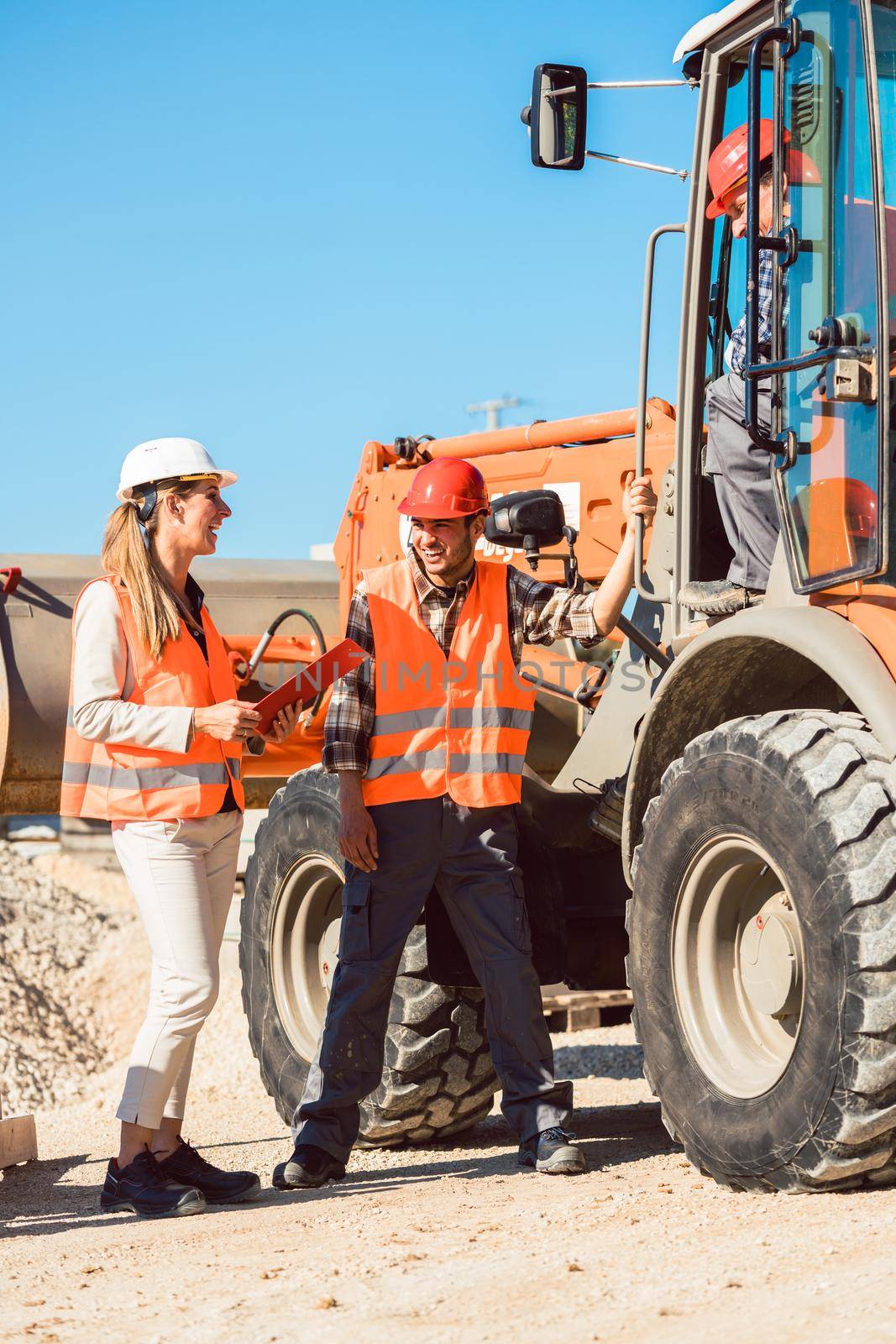 Civil engineer and worker discussion on road construction site, woman and man