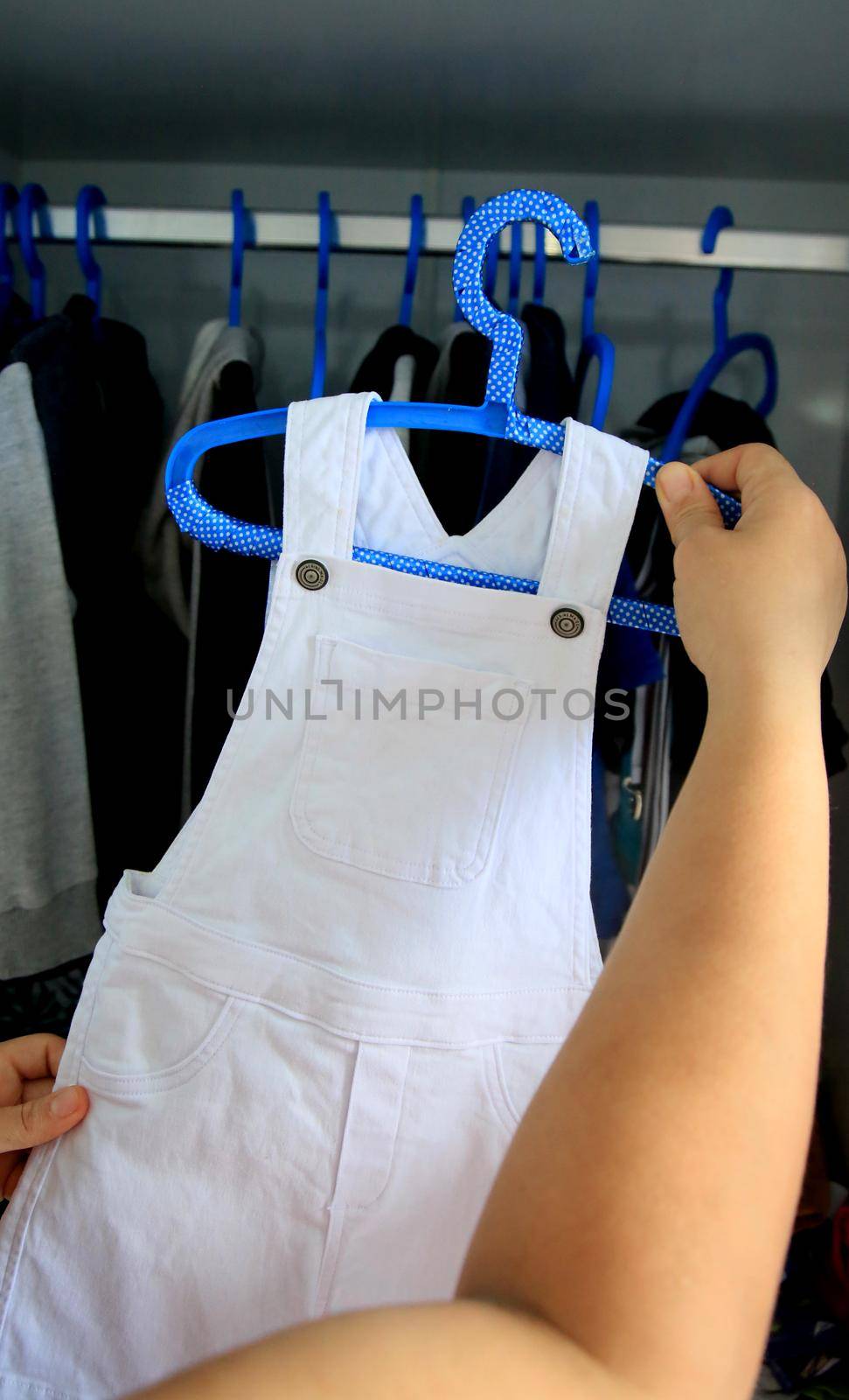 salvador, bahia / brazil - may 7, 2020: hands are seen picking up children's clothes on a hanger.