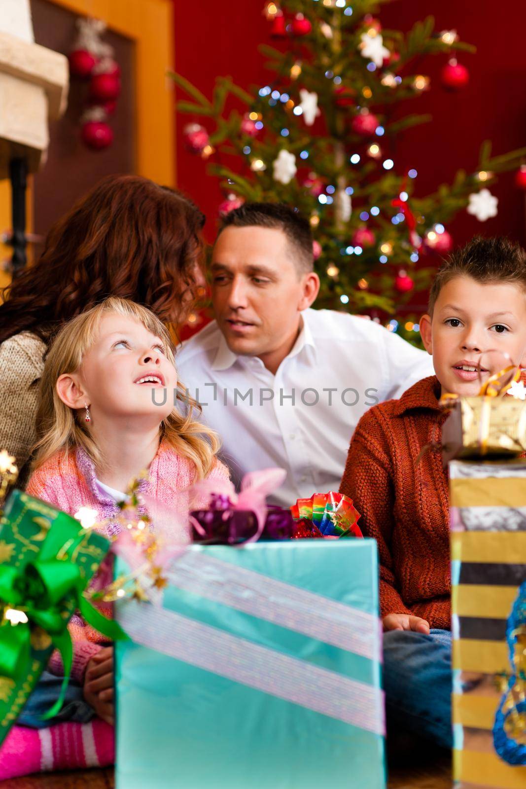 Christmas - happy family (parents with son and daughter) with gifts on Xmas Eve