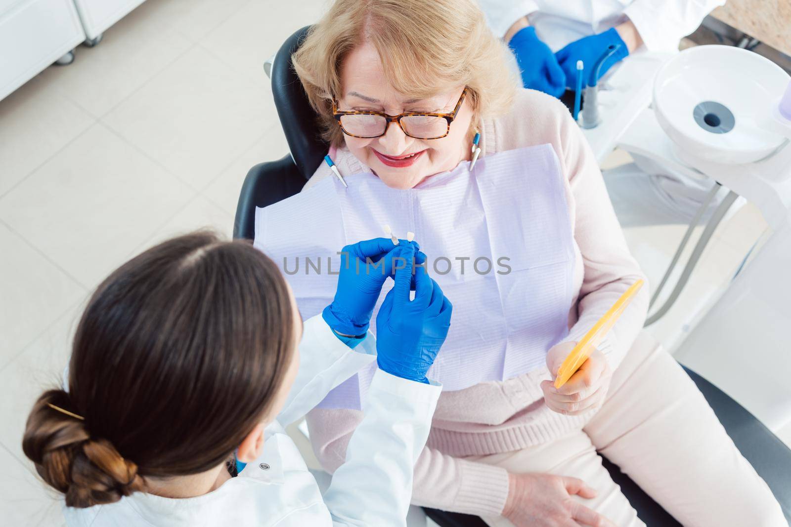 Dentist explain dental bleaching to patient showing color samples