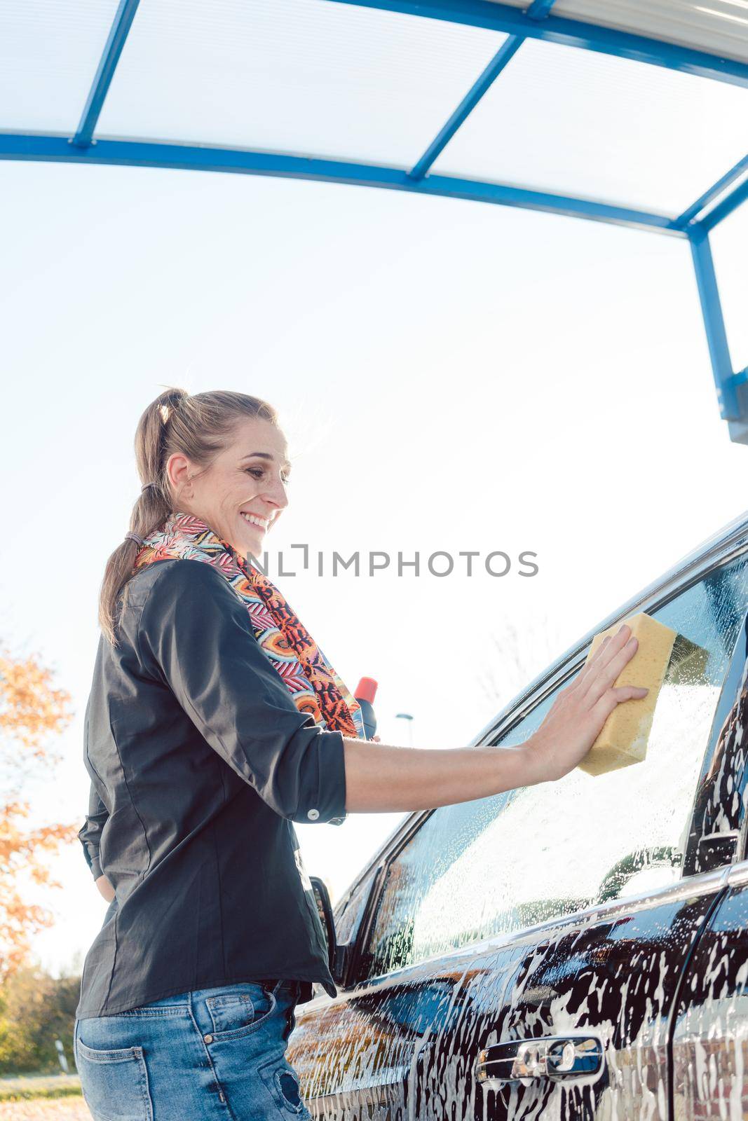 Woman foaming her car with sponge