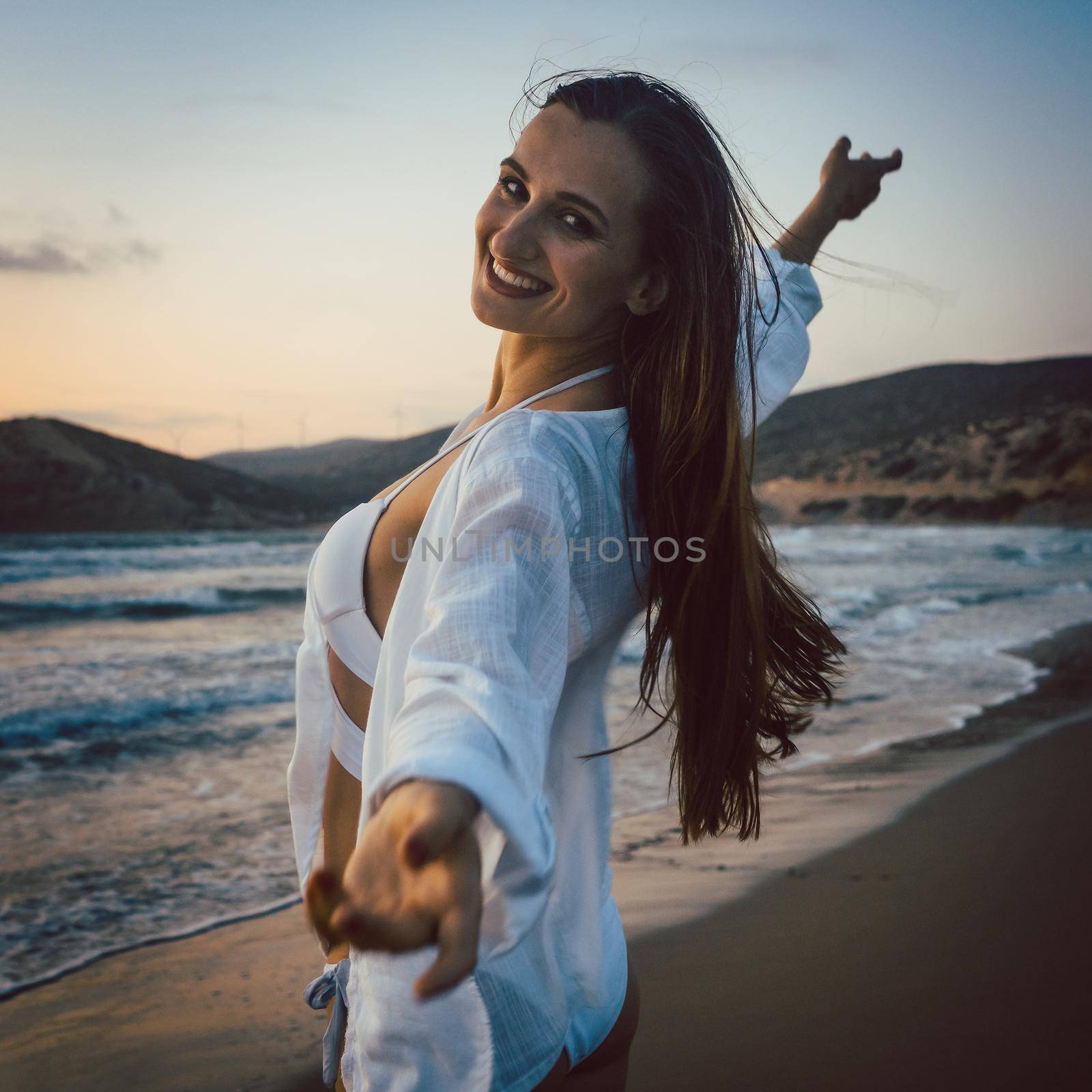 Woman having fun at the beach during sunset time by Kzenon