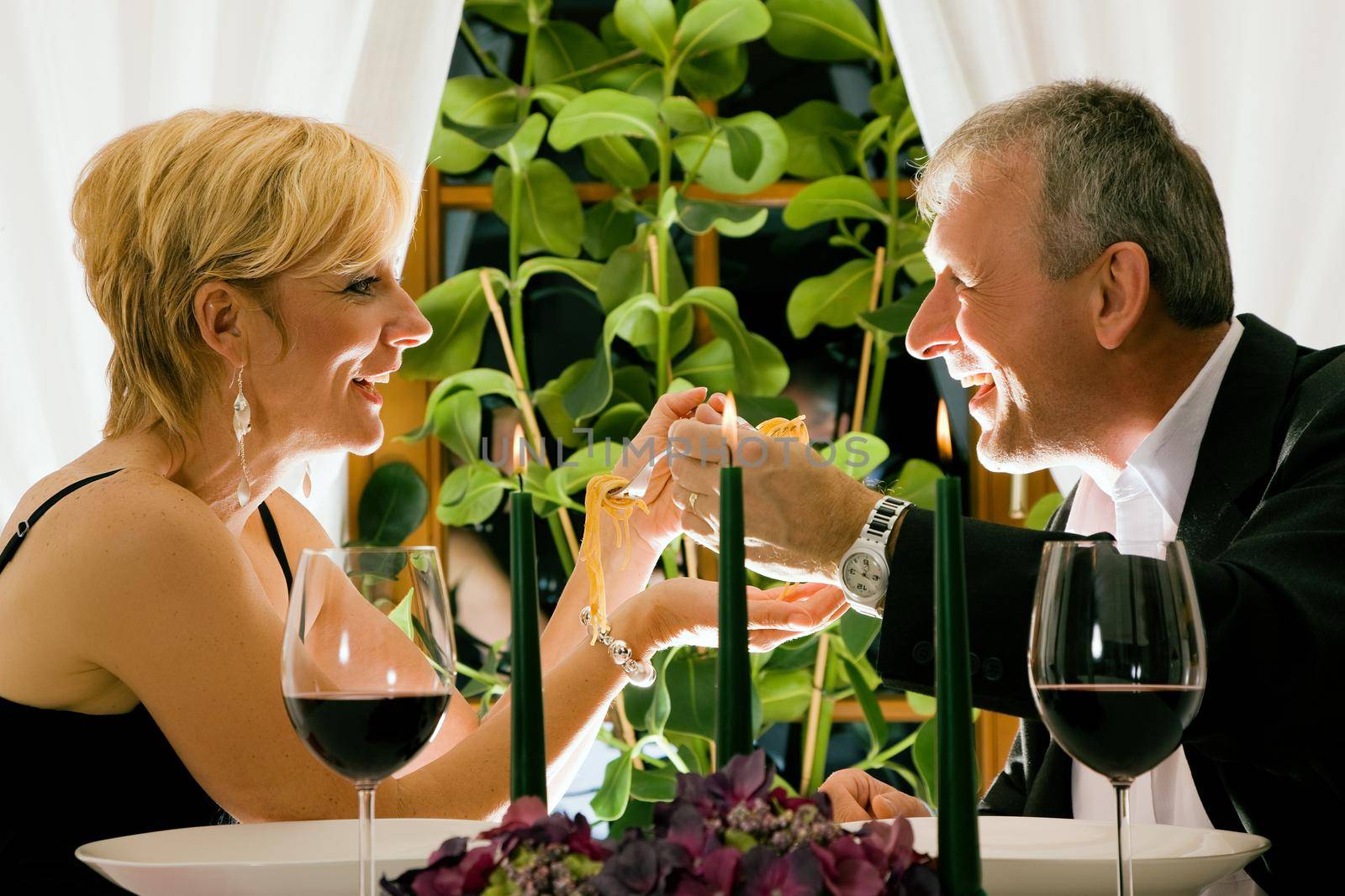 Couple having dinner in a restaurant, candles on the table, they are eating pasta