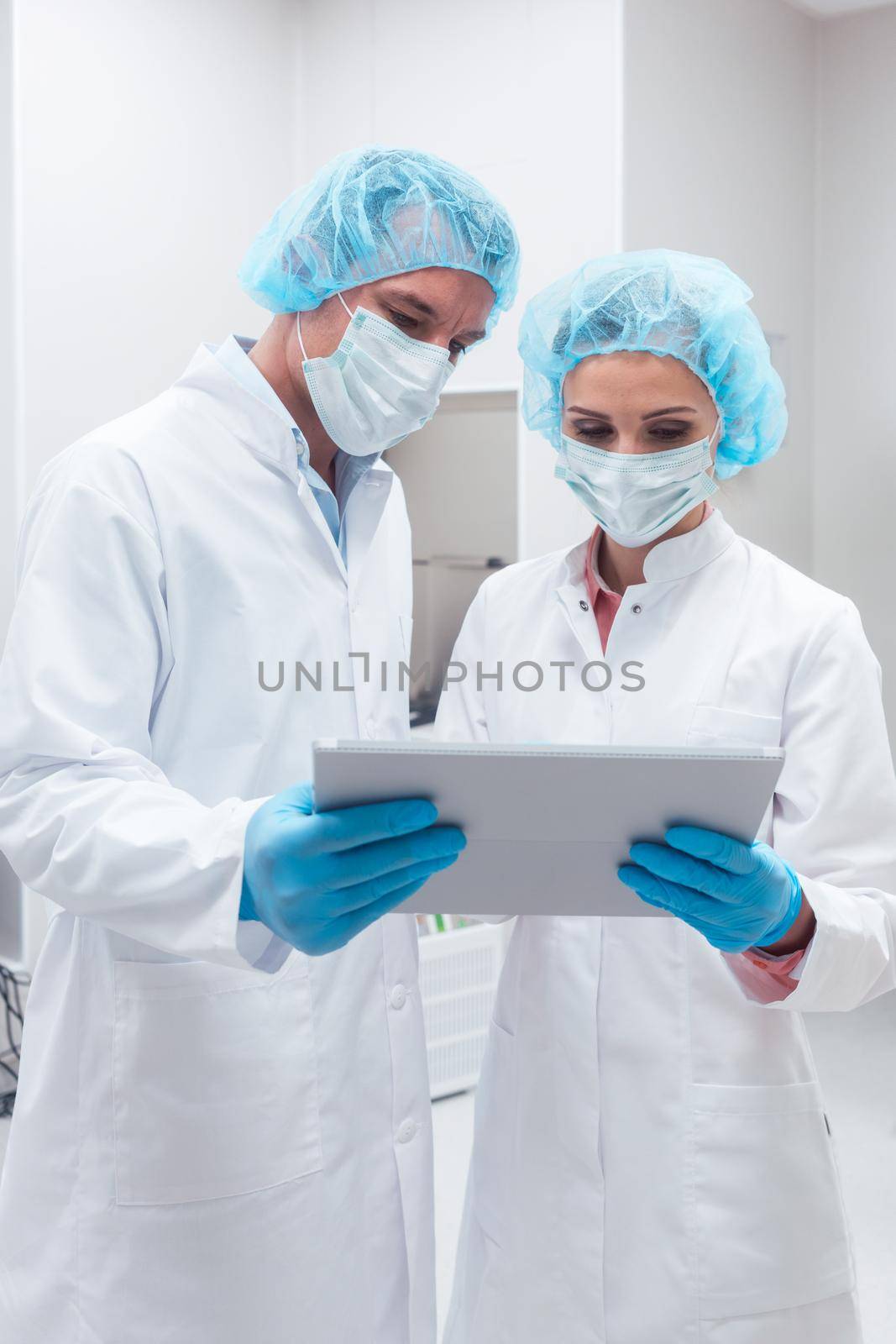 Two scientists working together in lab looking at data by Kzenon