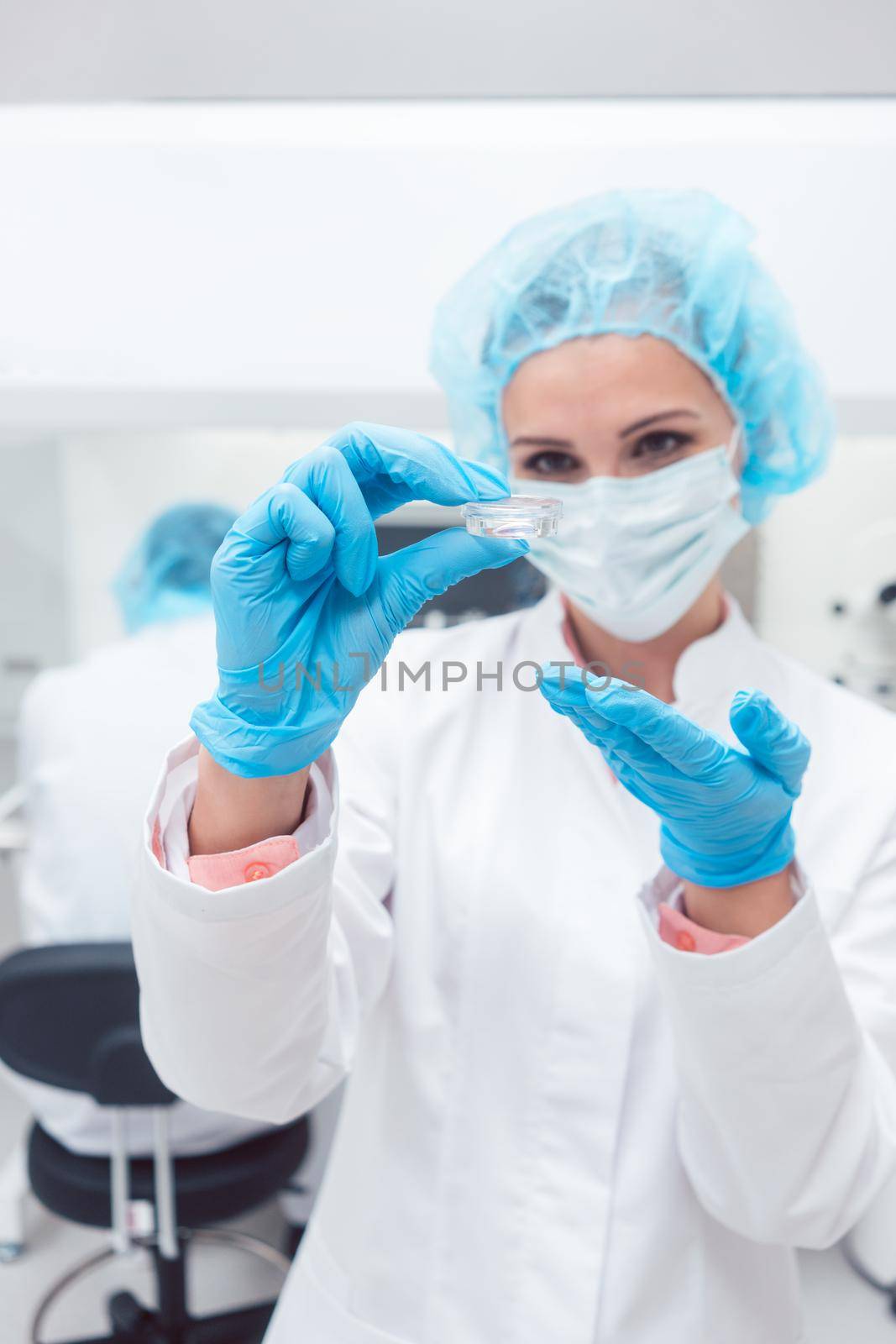 Woman scientist showing her newest biotech experiment in lab petri dish