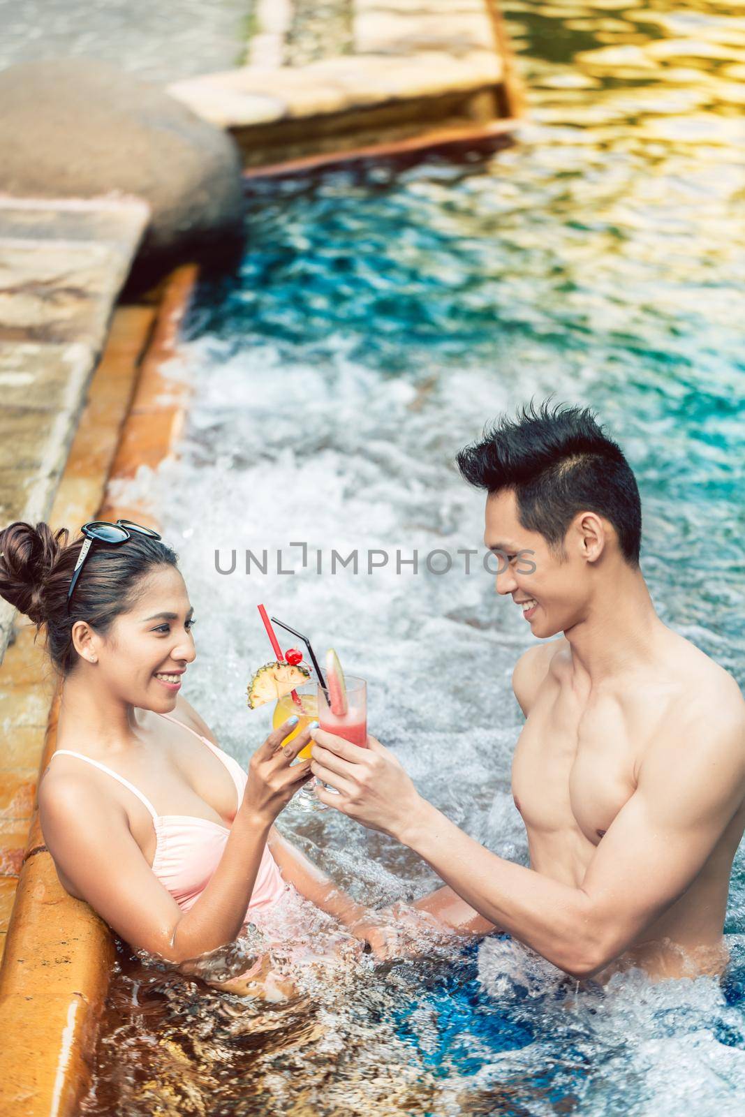 Young man flirting with an attractive woman in a trendy swimming pool by Kzenon