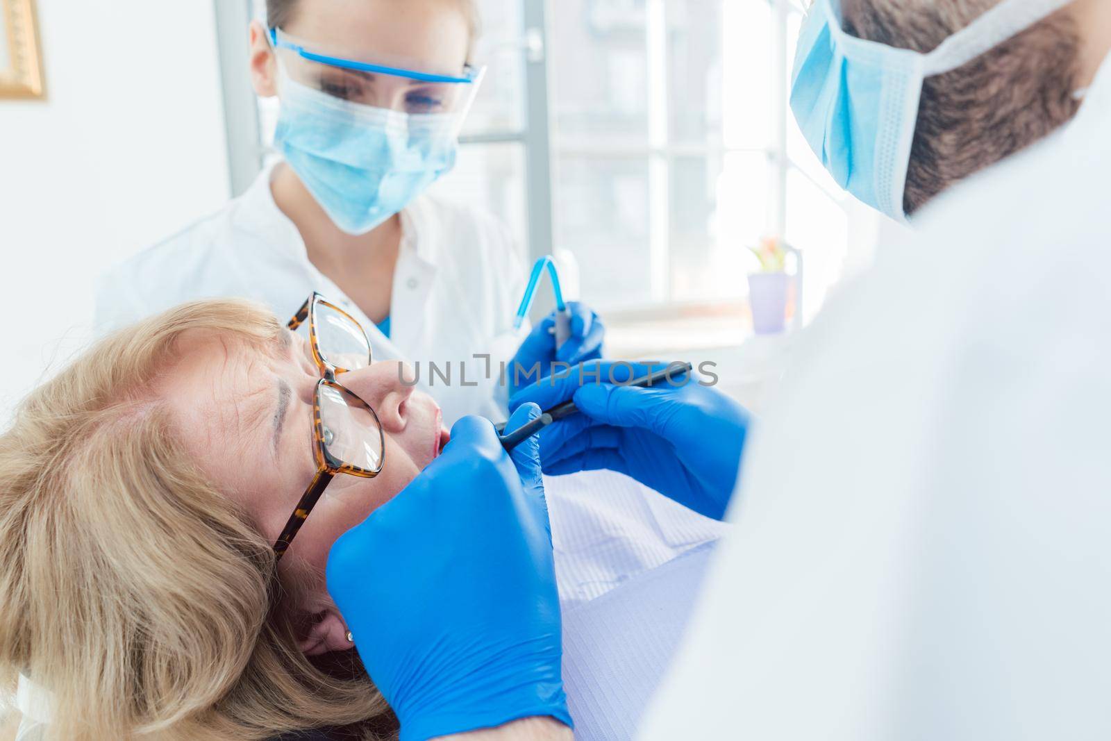Dentist during treatment of a senior patient by Kzenon