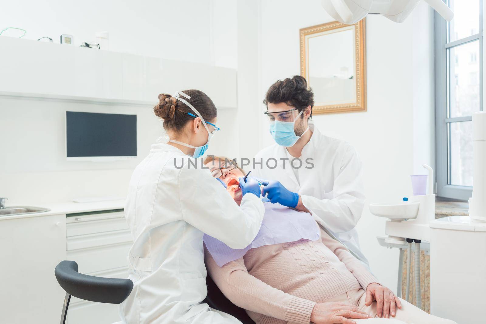 Dentist during treatment of senior patient woman looking into mouth