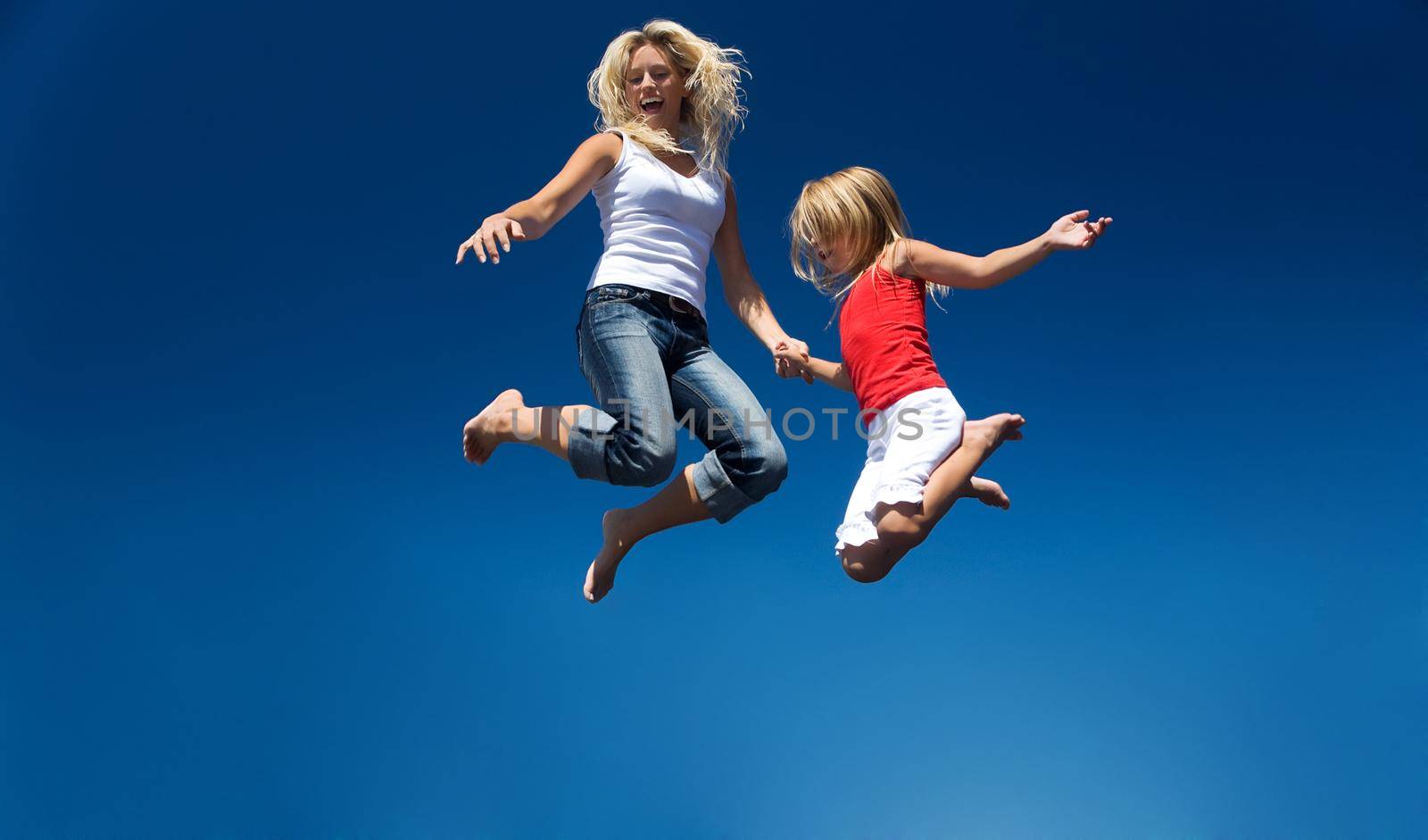 A mother and her daughter jumping high having lots of fun