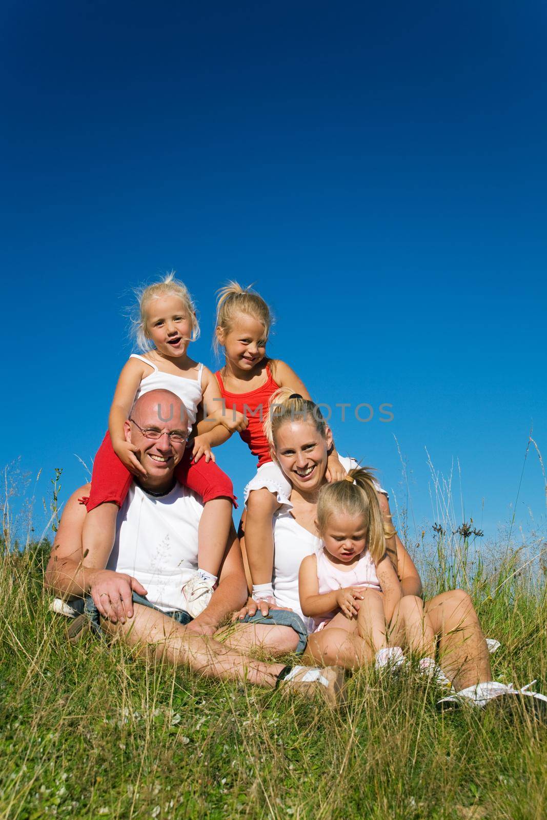 Family with three girls sitting in a meadow