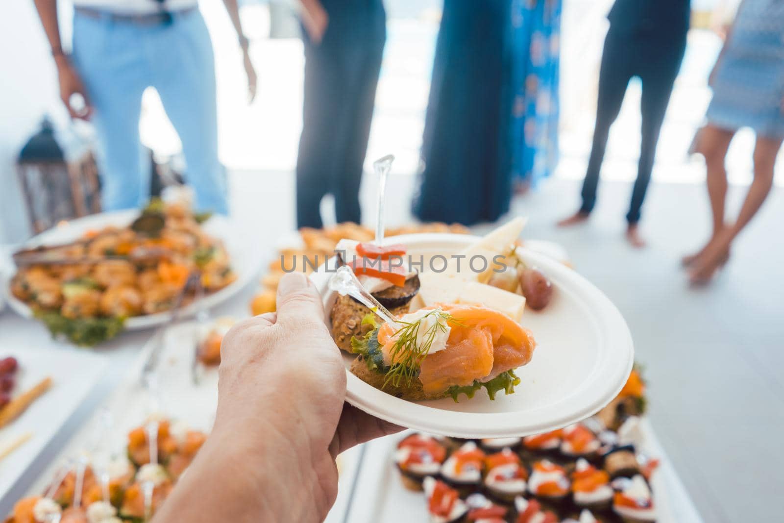 Man helping himself on Buffet of party outdoors taking food, point of view shot