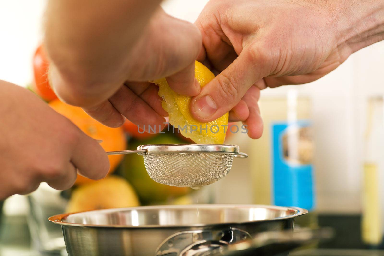People cooking, squeezing a lemon in order to prepare dessert