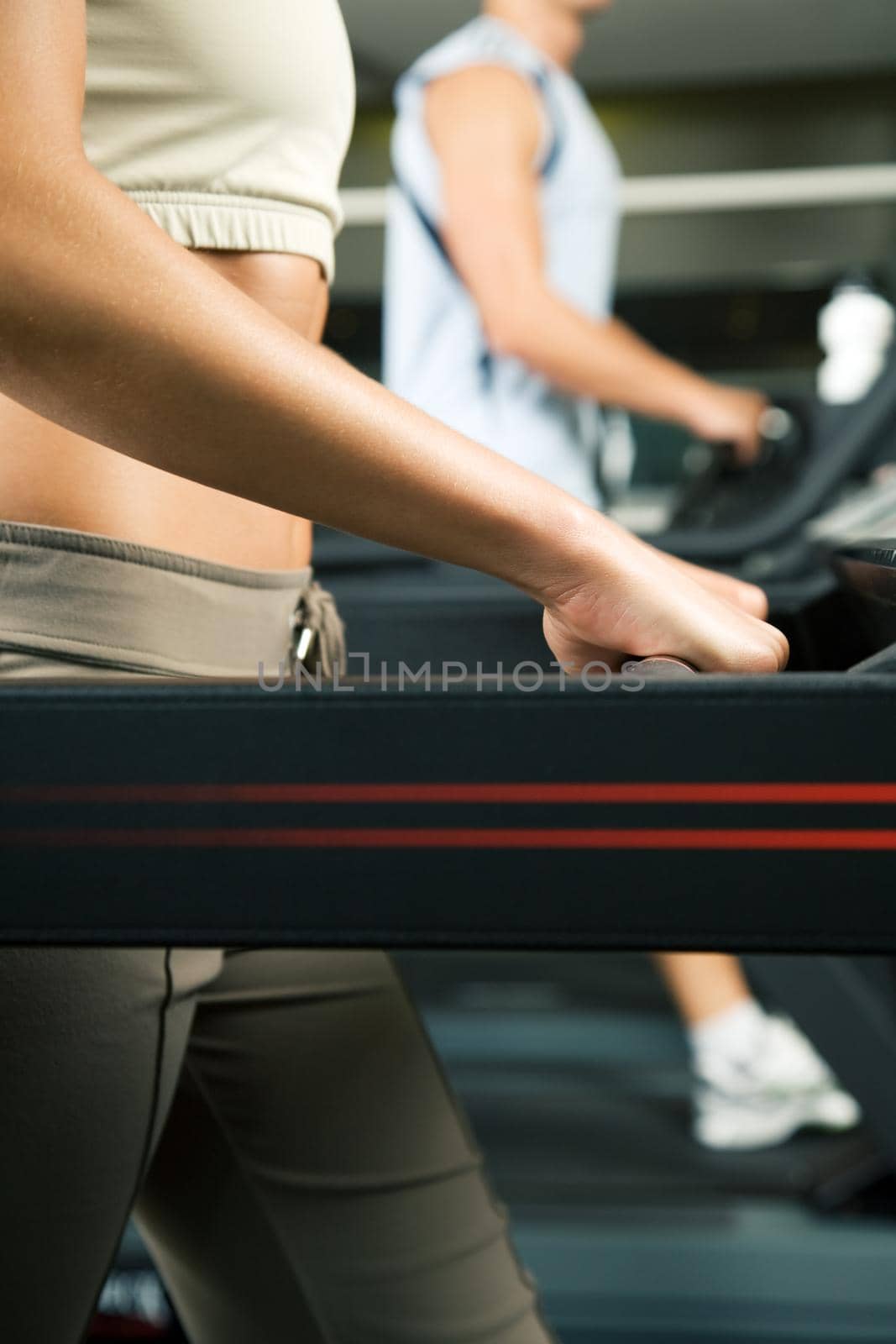 Two people (male / female) working out on a treadmill in a gym