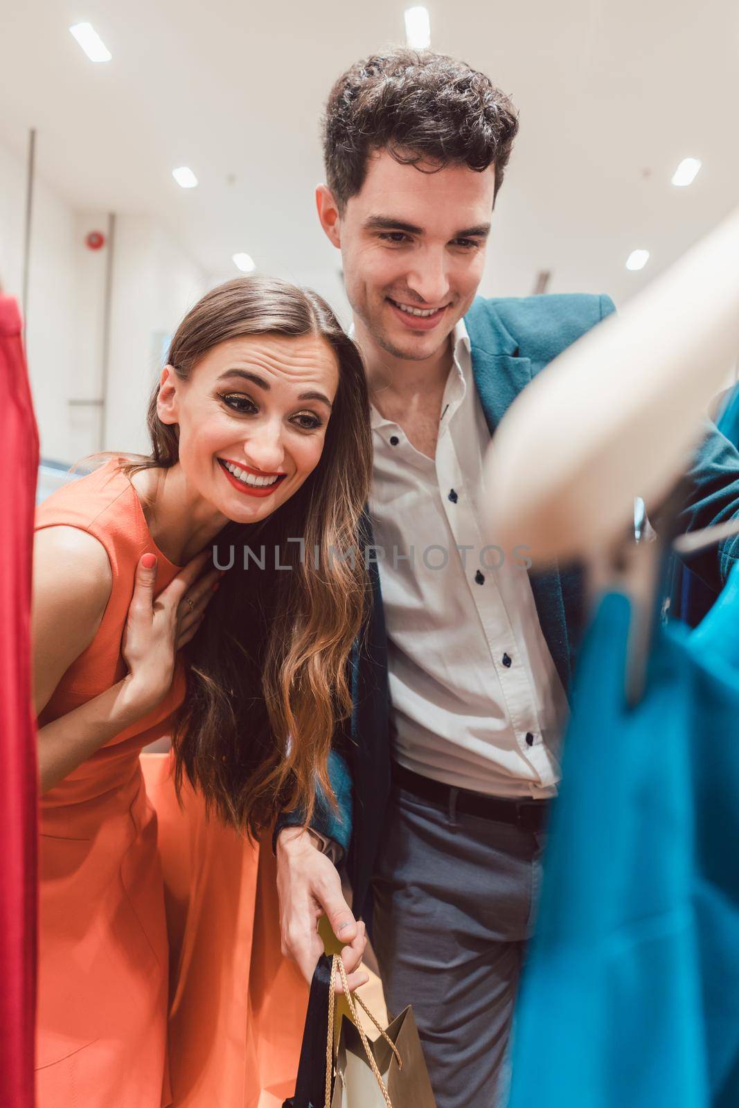 Couple checking the new arrivals in fashion boutique looking at dress colors