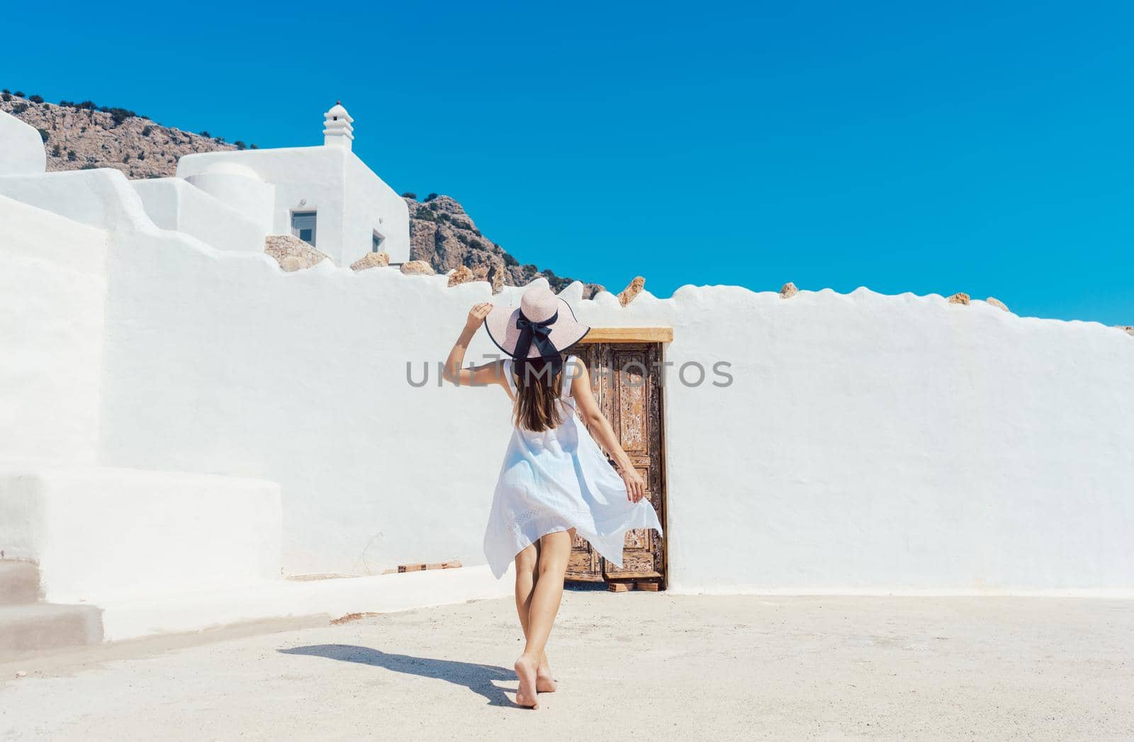 Woman approaching a greek house with a white wall