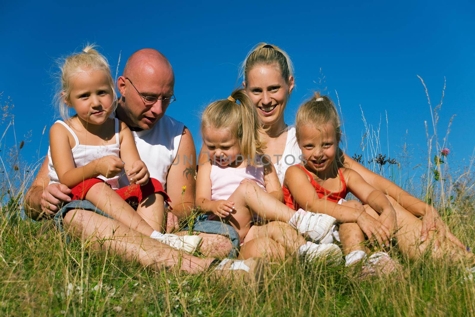 Family with three girls sitting in the grass