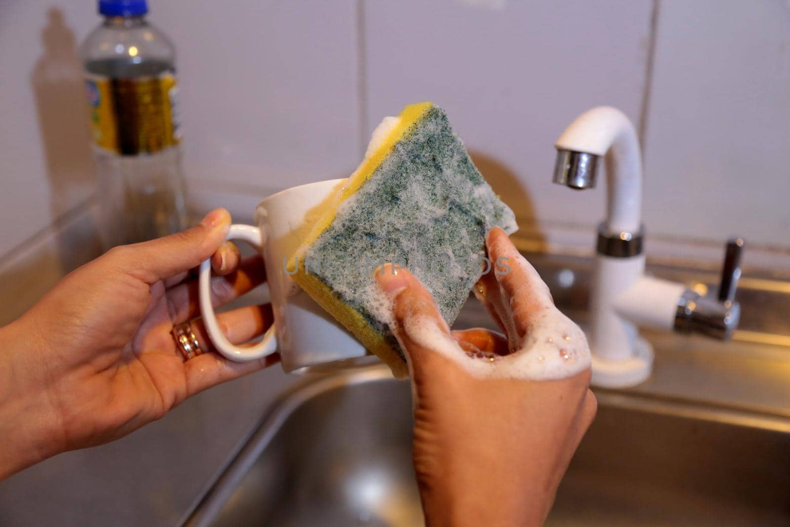 salvador, bahia / brazil - july 9, 2017: hand holds sponge for washing dishes in kitchen sink in the city of Salvador.