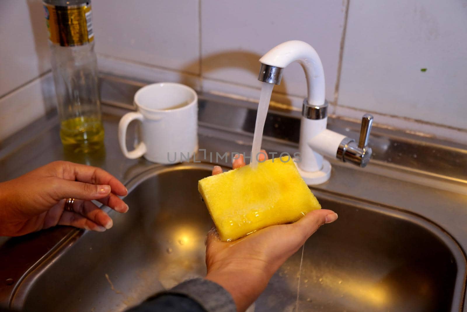 salvador, bahia / brazil - july 9, 2017: hand holds sponge for washing dishes in kitchen sink in the city of Salvador.