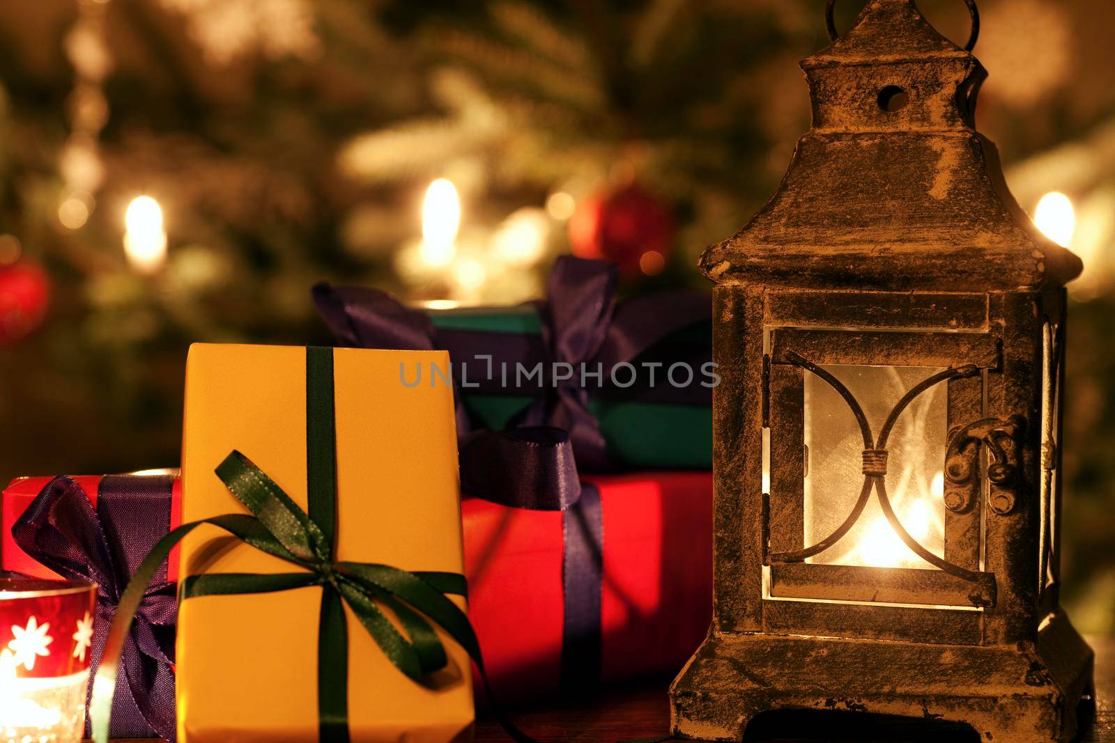 Christmas still life with presents and a lantern, the Christmas tree and baubles in the background