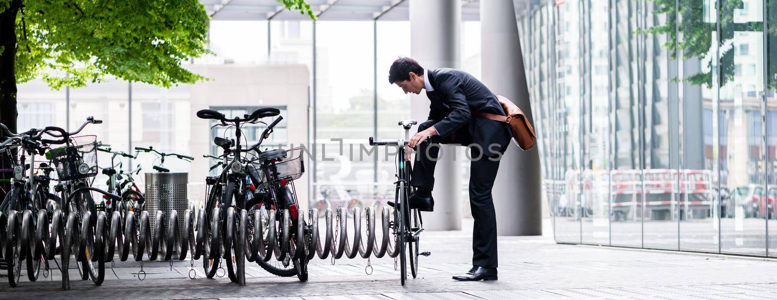 Businessman parking his bicycle in town by Kzenon
