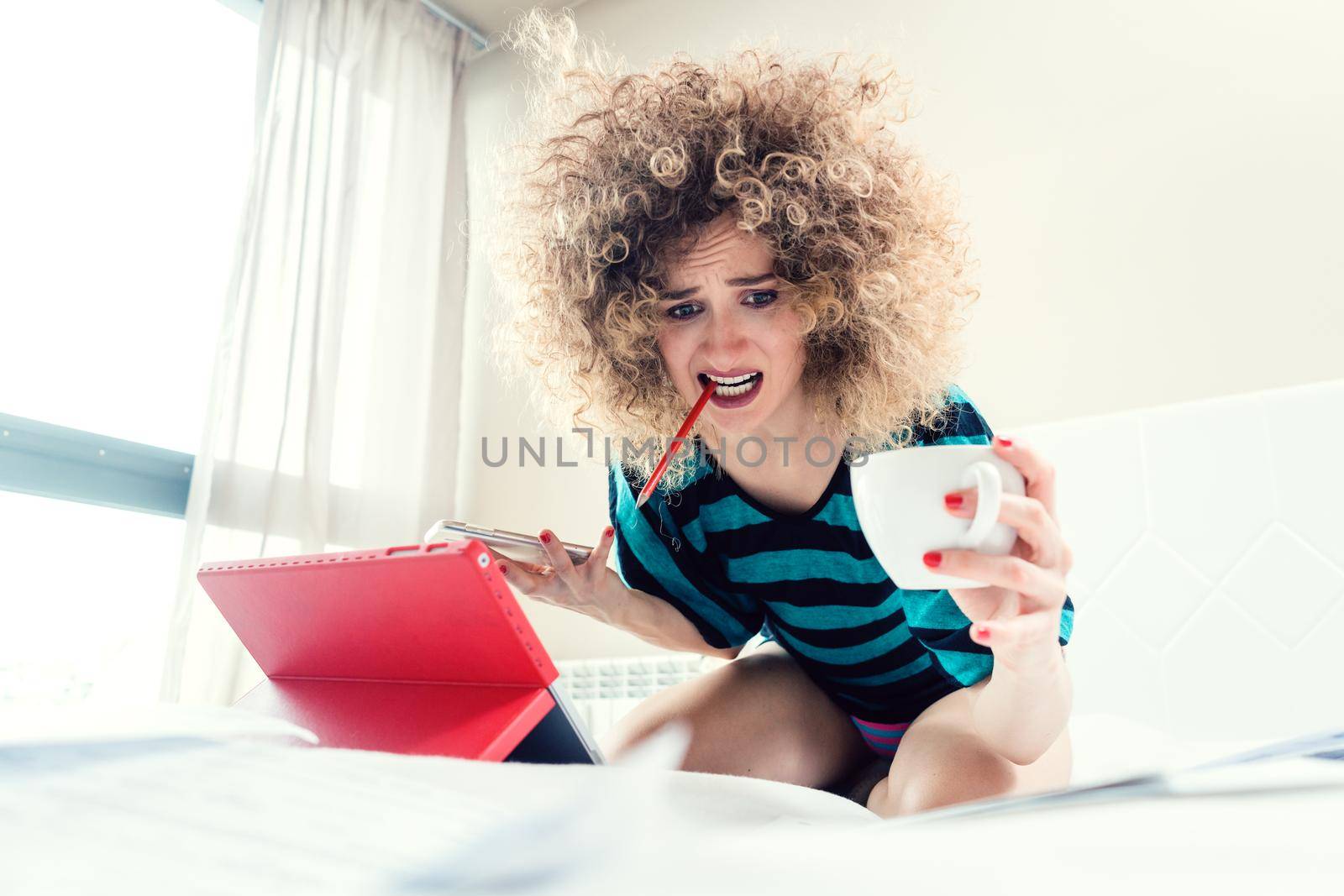 Woman student on her bed learning for exam in panic and despair