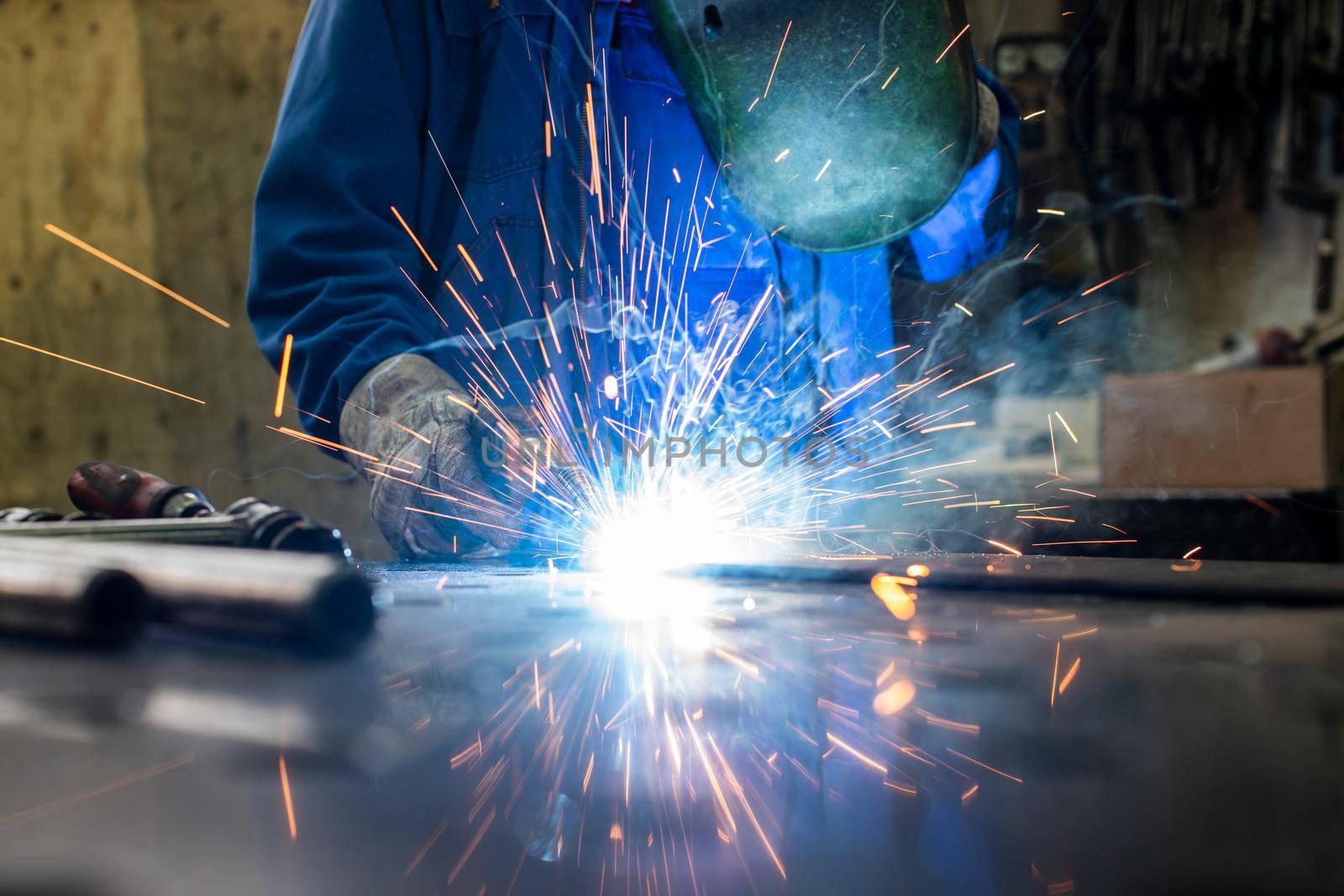 Welder in his workshop welding metal, lots of sparks flying around