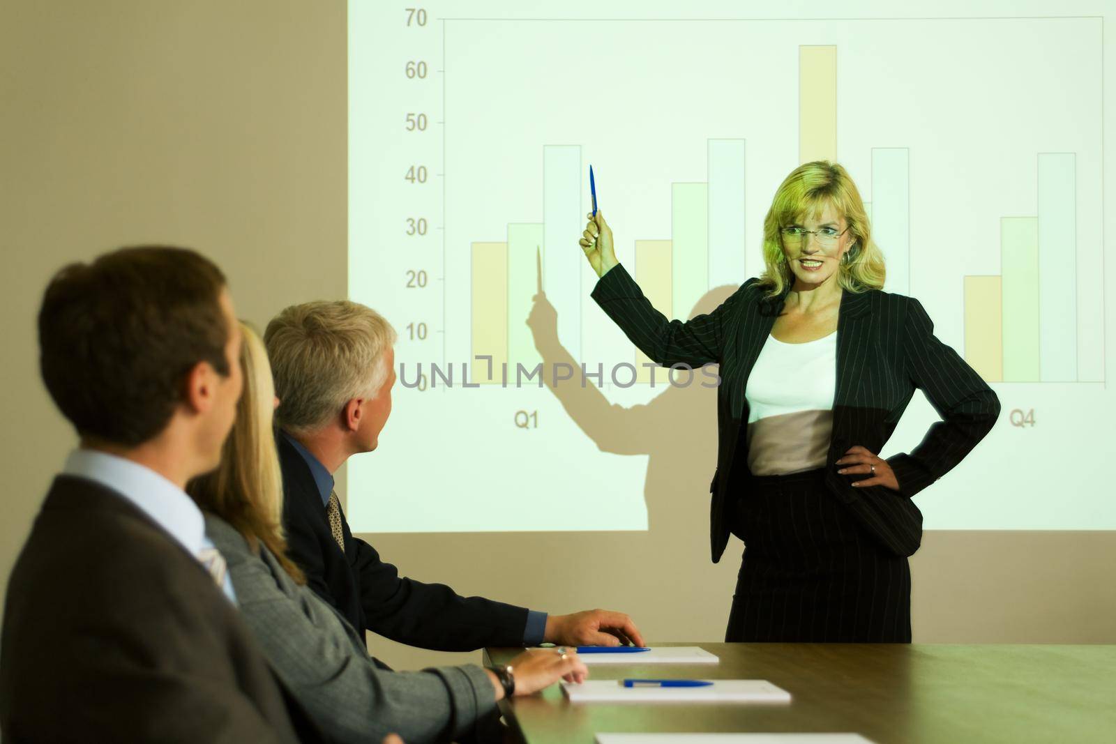 A group of people in a video presentation held by a blond woman